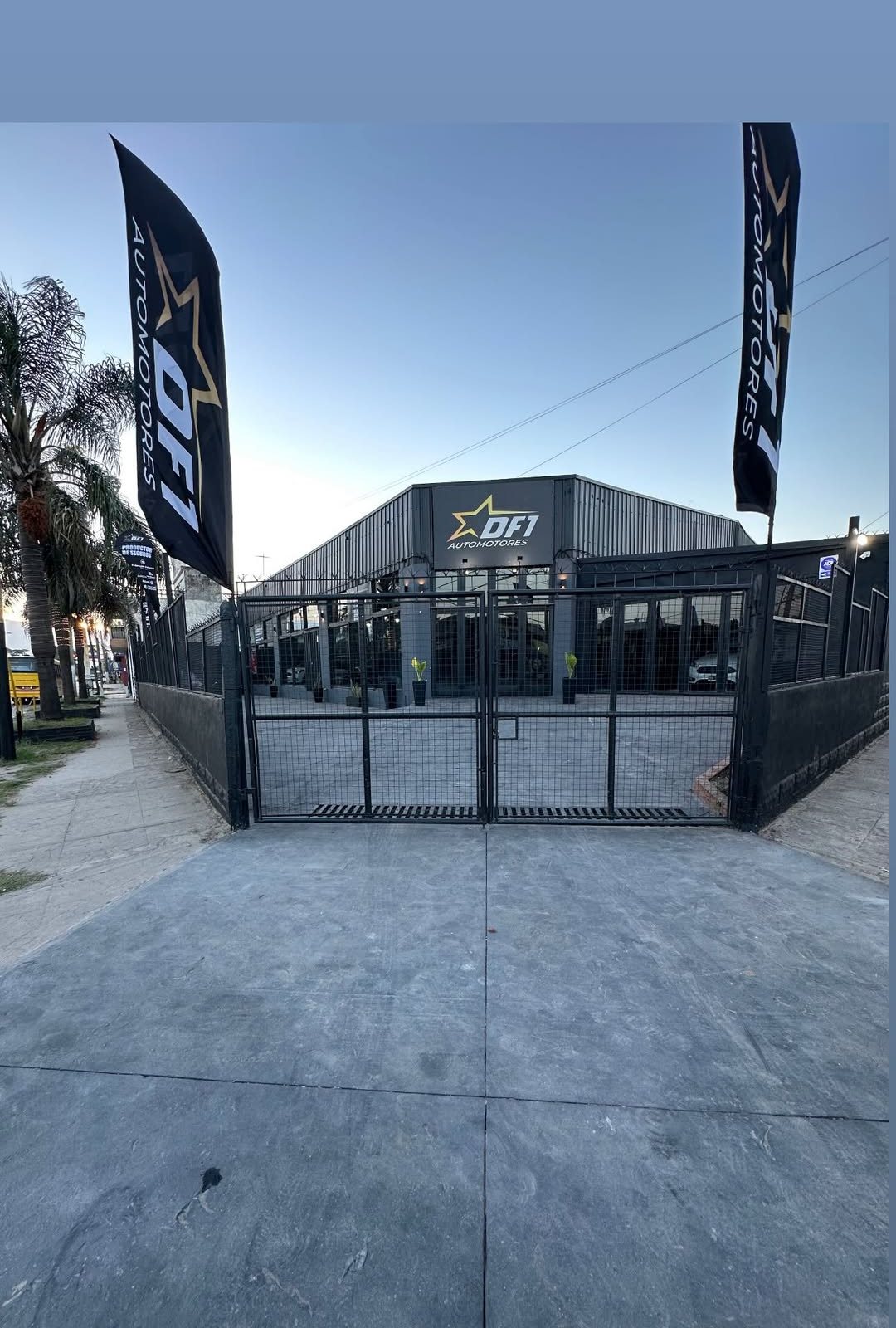 Fachada de DF1 Automotores sobre Ruta 197, con las banderas y el portón